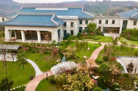 A modern building with a blue roof, surrounded by well-maintained gardens and a curved pathway.