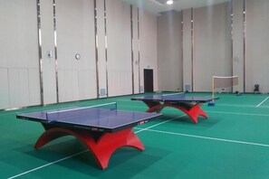 Two ping pong tables in a room with a green floor and white walls. - Xiaolangdi Zhongzhou International Hotel (Jiyuan)