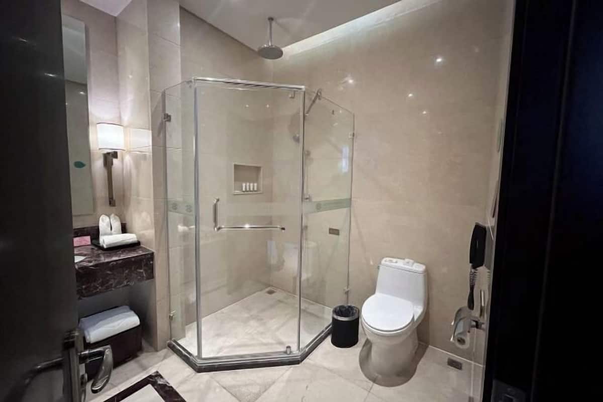 A modern bathroom with a glass-enclosed shower, a toilet, and a marble-tiled floor.