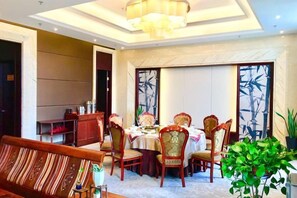A dining area with a round table, chairs, and a chandelier.