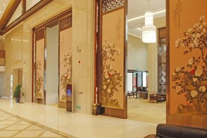 A hotel lobby with traditional decor, a reception desk, and a seating area.