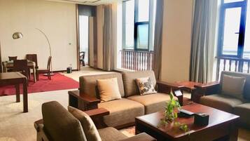 A hotel living room with a sofa set, a coffee table, and a dining table.