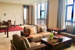 Un salón de hotel con un conjunto de sofás, una mesa de centro y una mesa de comedor.