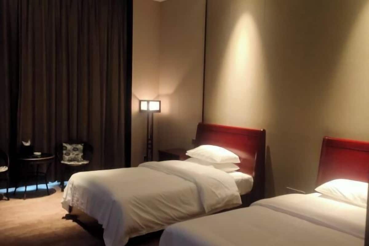 Et hotelværelse med to senge, et skrivebord, en stol og en lampe.