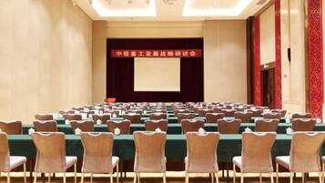 A conference room with rows of chairs, a stage, and a screen.