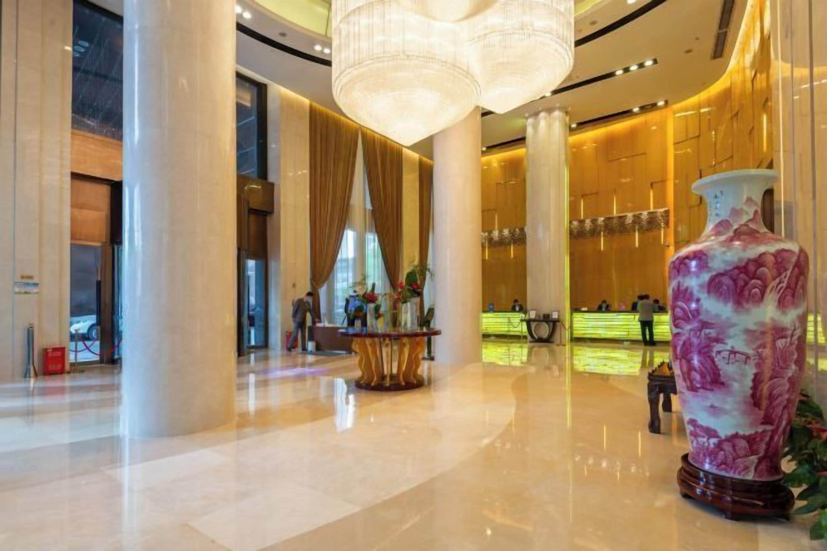 Un amplio vestíbulo con techos altos, columnas imponentes y un llamativo jarrón decorativo.