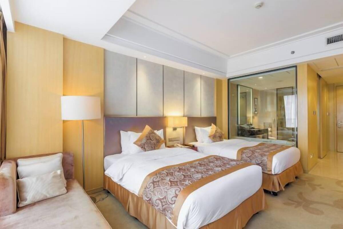 Habitación de hotel con dos camas, un sofá y un espejo grande.