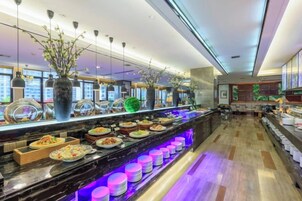 Un bufé con distintos alimentos, una barra de mármol y una zona de estar con mesas y sillas.