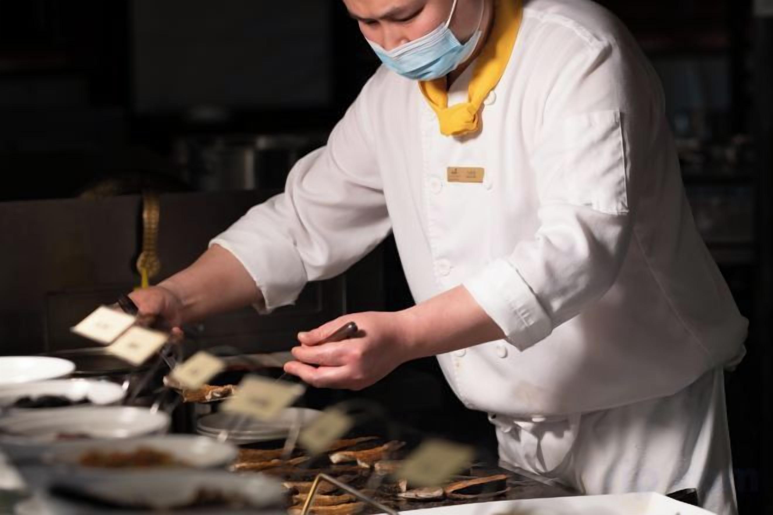 Un chef con uniforme blanco preparando comida en una cocina.