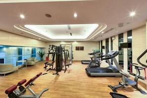 Une salle de sport moderne équipée de machines de cardio, de matériel de musculation et d’un espace détente offrant une vue sur la ville.