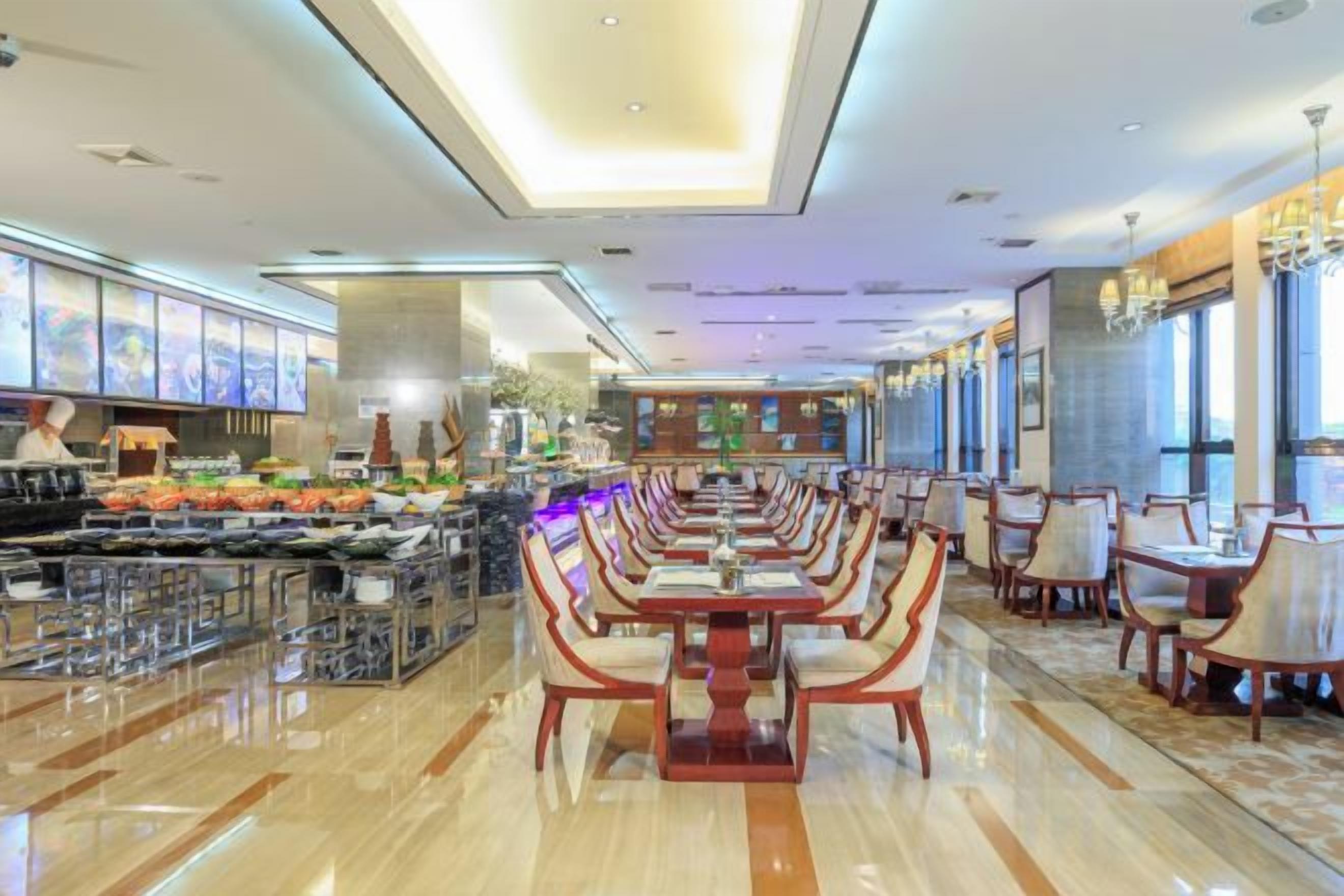 Un restaurante amplio con una barra larga, varias mesas para comer y sillas.