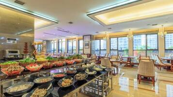 Zona de buffet con diferentes opciones de comida y un área de estar con mesas y sillas.