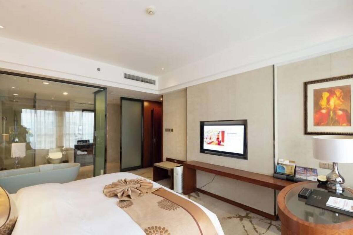 Una habitación de hotel con cama, escritorio, televisión y mostrador de recepción.