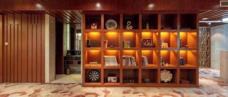 A room with a wooden bookshelf, patterned carpet, and a ceiling with recessed lighting.