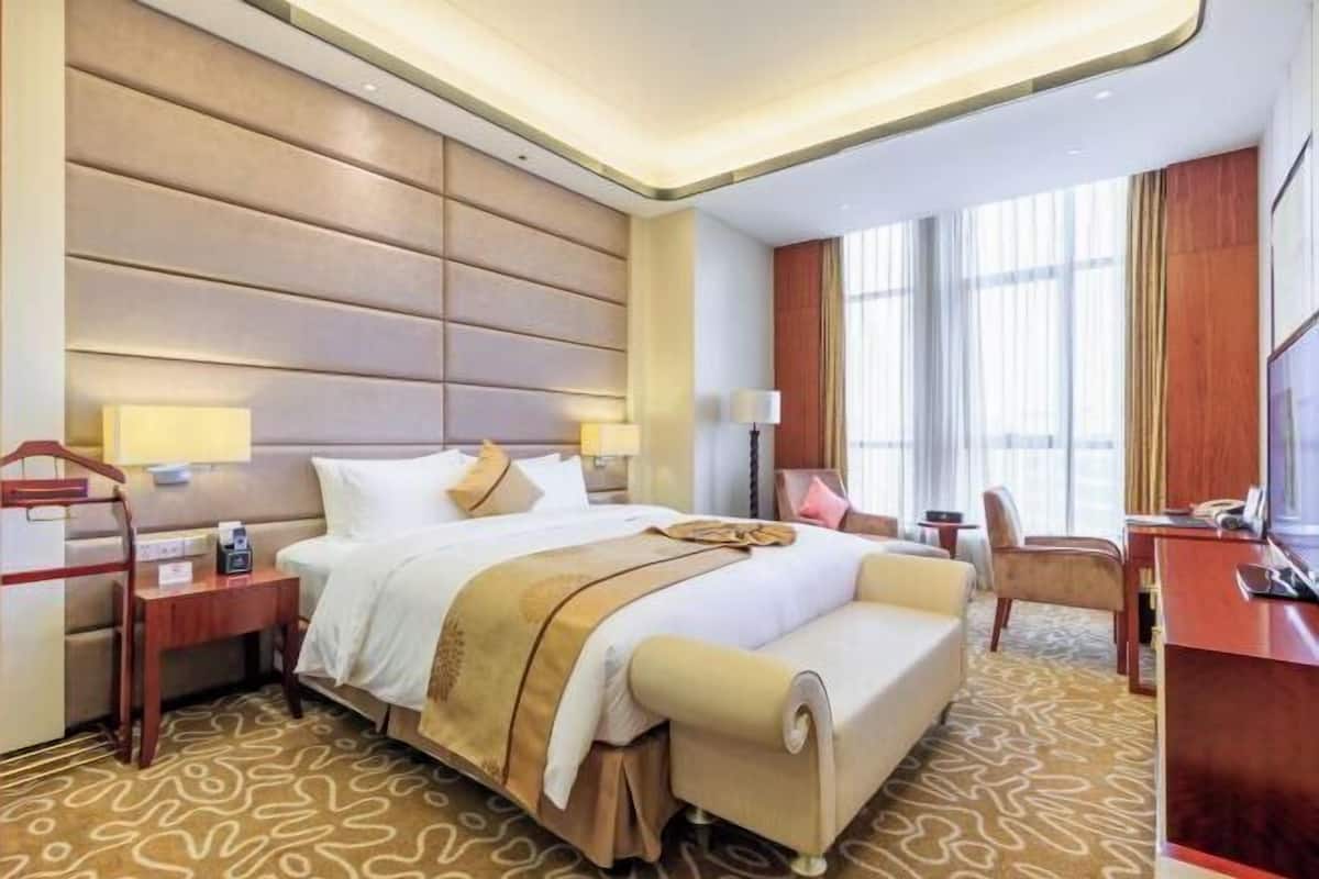 Una habitación de hotel con una cama grande, mesitas de noche, un escritorio y una silla.