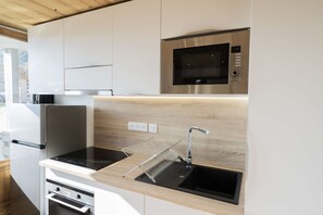 Een moderne keuken met inbouwapparatuur, een roestvrijstalen magnetron en een zwart inductiekookplaat.