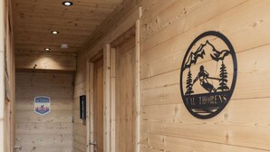 A wooden interior hallway with a logo on the wall, a door, and a sign on the wall. - Superb apartment for 4 people, 30m², 2 sleeping areas, renovated, at the foot of the slopes (VAL THORENS)