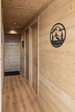 A wooden interior hallway with a logo on the wall, a door, and a sign on the wall. - Superb apartment for 4 people, 30m², 2 sleeping areas, renovated, at the foot of the slopes (VAL THORENS)