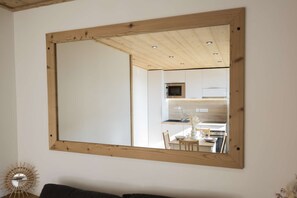 A room with a large mirror, a dining table with chairs, and a kitchen area visible through the mirror. - Superb apartment for 4 people, 30m², 2 sleeping areas, renovated, at the foot of the slopes (VAL THORENS)