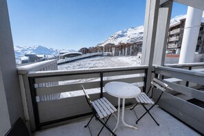 A balcony with a table and chairs, overlooking a snowy landscape and buildings. - Superb apartment for 4 people, 30m², 2 sleeping areas, renovated, at the foot of the slopes (VAL THORENS)
