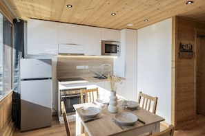 A modern kitchen with white cabinets, a built-in microwave, and a wooden ceiling. - Superb apartment for 4 people, 30m², 2 sleeping areas, renovated, at the foot of the slopes (VAL THORENS)