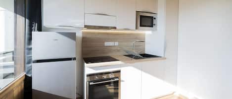A compact kitchen with a built-in microwave, oven, and a small countertop.