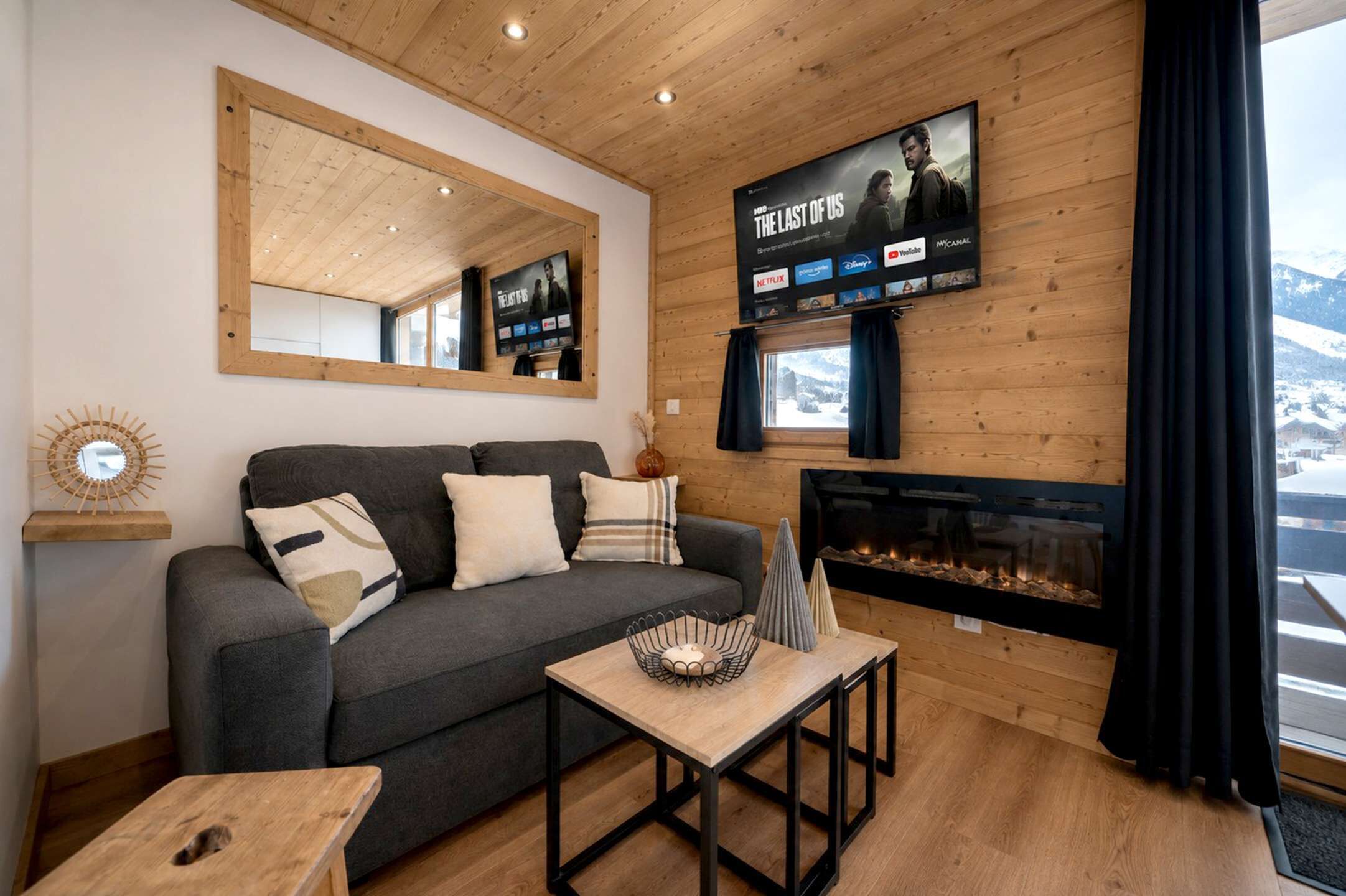 Una sala de estar acogedora con un sofá, una mesa de centro, una chimenea y un televisor montado que muestra un cartel de película.