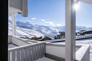 A balcony with a view of snow-covered mountains and a modern building in the background. - Superb apartment for 4 people, 30m², 2 sleeping areas, renovated, at the foot of the slopes (VAL THORENS)