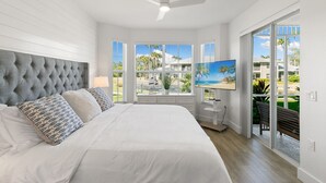 A bedroom with a large bed, a ceiling fan, and a view of a beach through large windows. - LUXURY 1st FLOOR VILLA / 2 BD 2BTH in Lely Resort (Naples)