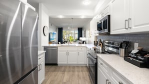 A modern kitchen with stainless steel appliances, white cabinetry, and a coffee bar. - LUXURY 1st FLOOR VILLA / 2 BD 2BTH in Lely Resort (Naples)