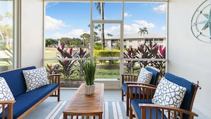 A sunlit patio with a wooden table, blue cushioned chairs, and a potted plant. - LUXURY 1st FLOOR VILLA / 2 BD 2BTH in Lely Resort (Naples)