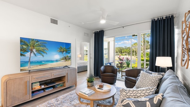 A modern living room with a flat-screen TV, a sofa, a coffee table, and a view of the outdoors. - LUXURY 1st FLOOR VILLA / 2 BD 2BTH in Lely Resort (Naples)