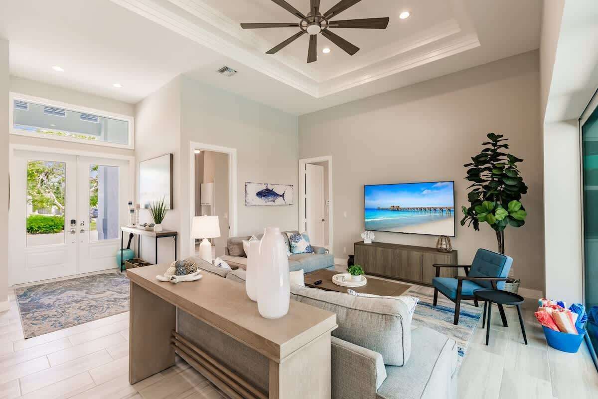 A modern living room with a central island, a large flat-screen TV, and a ceiling fan.