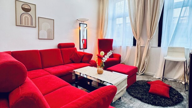 Una sala de estar moderna con un sofá seccional rojo, una mesa de centro y obras de arte en las paredes.