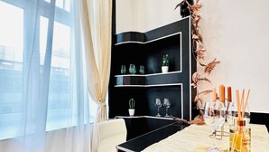Una habitación moderna con un estante negro, una mesa de comedor con velas y vistas a través de un ventanal.