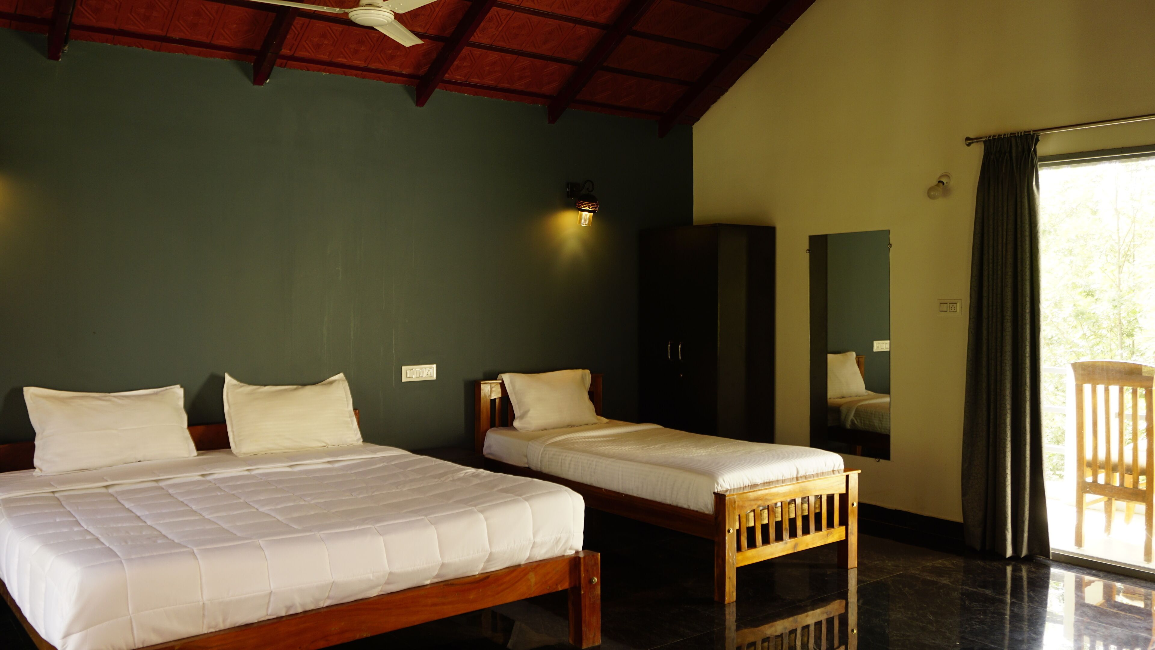 A room with two beds, a ceiling fan, a wardrobe, and a window with curtains.