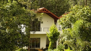Et moderne hus i to etager omgivet af frodig vegetation.