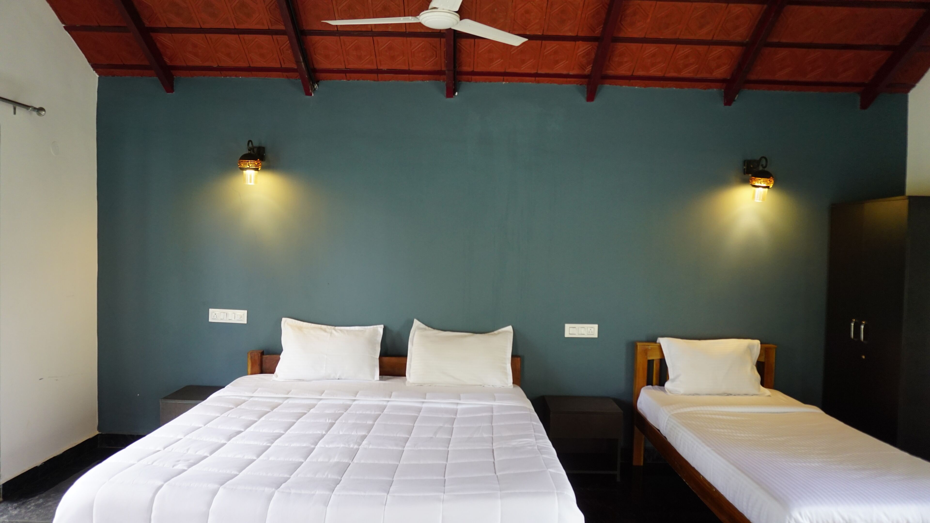 A room with a large bed, two bedside tables, a wardrobe, and a ceiling fan.