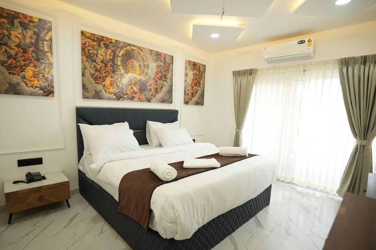 Una camera d'albergo con un letto grande, un comodino e opere d'arte alle pareti.