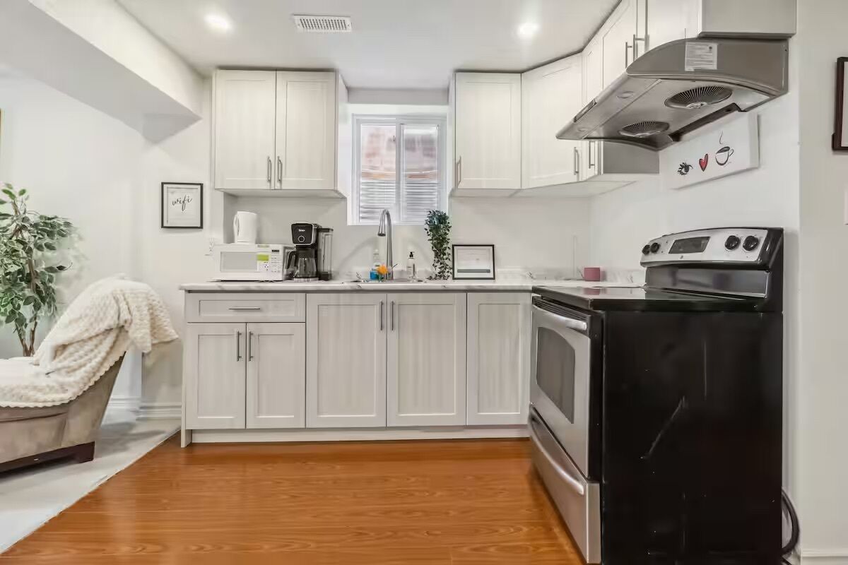 A modern kitchen with white cabinets, a black refrigerator, and a stainless steel oven.