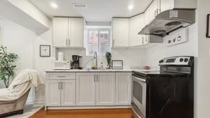 Una cocina moderna con armarios blancos, un refrigerador negro y un horno de acero inoxidable.