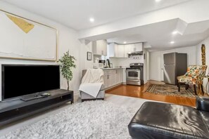 A modern living room with a flat-screen TV, a fluffy white rug, a leather sofa, and a dining area with a patterned rug. - 5 minutes from Ridgeway Plaza! Bright Basement retreat in Mississauga (Mississauga)