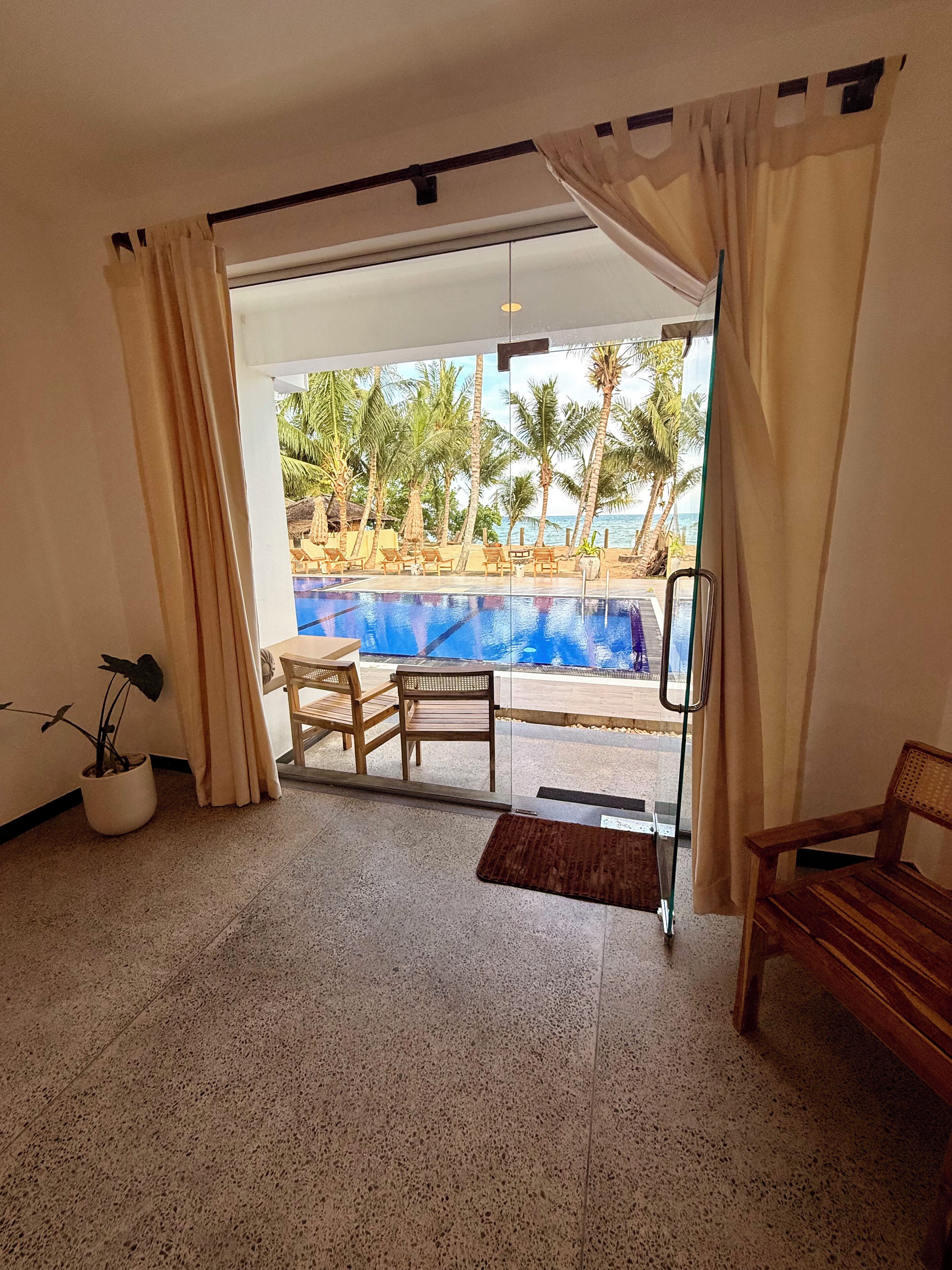 Quarto com porta de vidro que dá para uma área de piscina, um vaso de planta e um banco de madeira.