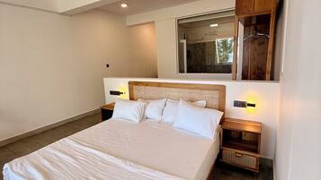 A modern bedroom with a large bed, wooden headboard, bedside tables, and a mirror.
