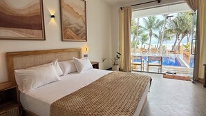 A hotel room with a large bed, a ceiling fan, and a view of a pool and palm trees. - OLA Tangalle (Tangalle)