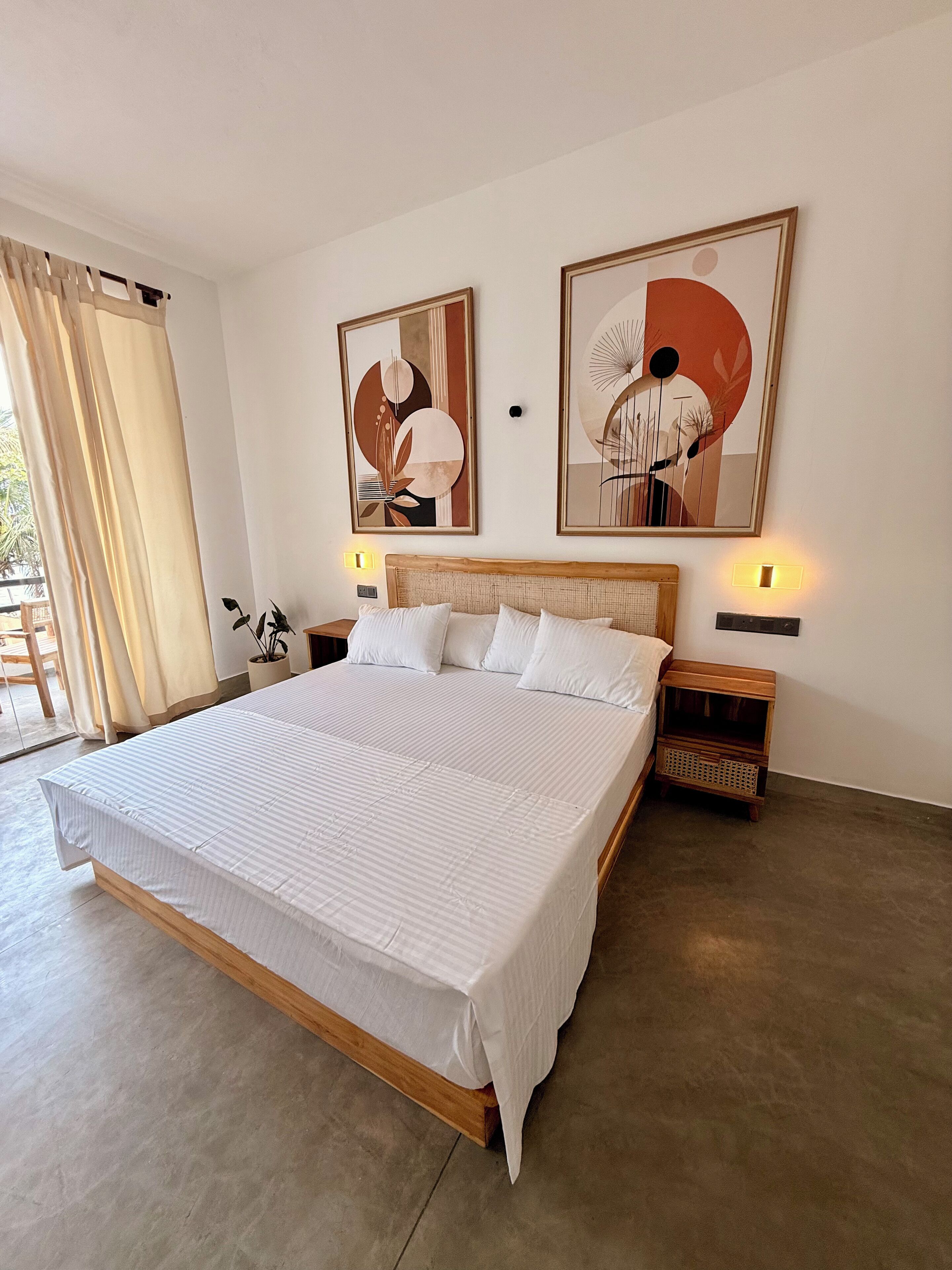 A large bed with a wooden frame, two bedside tables with lamps, and abstract artwork on the walls.