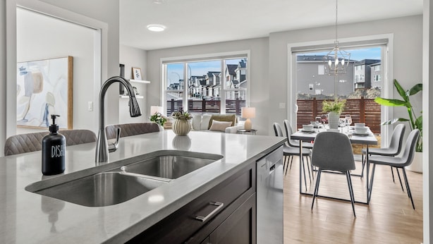 Una cocina moderna con una isla grande, pileta doble y comedor con sillas y una mesa.