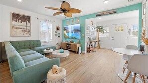 A modern living room with a green sofa, a round coffee table, and a ceiling fan. - Coastal Comfort 2BR Getaway St Pete (St. Petersburg)