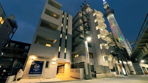 A modern building with a sign for Asakusa Sky Hotel, featuring a prominent tower with colorful lights. - Asakusa Sky Tokyo Condominium hotel (Tokyo)