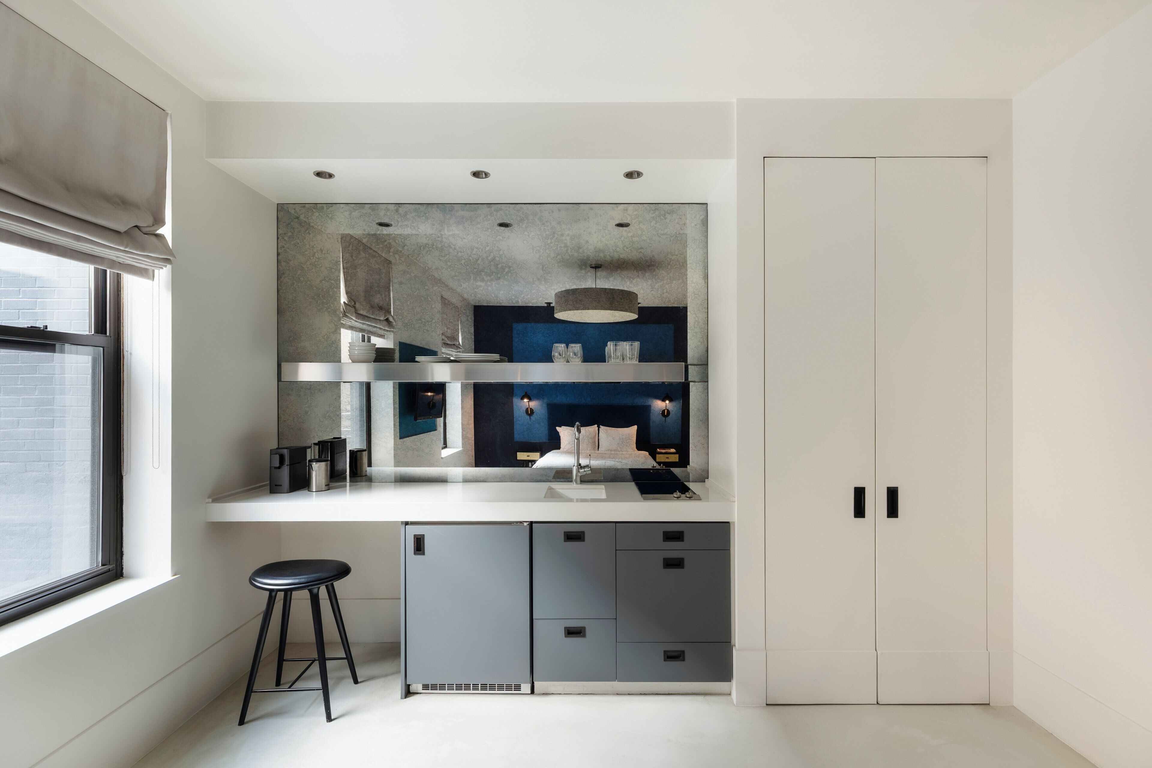 A modern kitchen with a built-in stove, a sink, and a countertop. There is a window on the left side and a door on the right.
